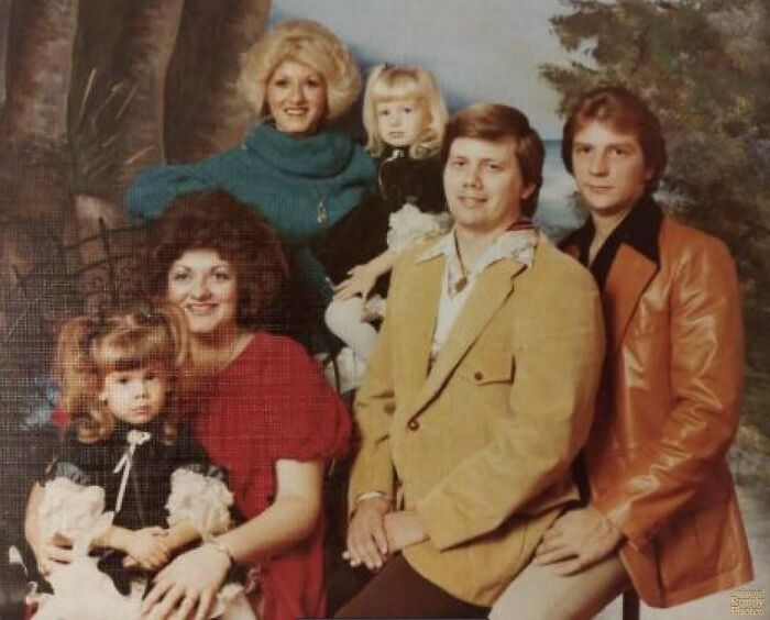 Awkward family photo from the 70s showing six relatives dressed in vintage clothing with warm smiles and posed indoors.