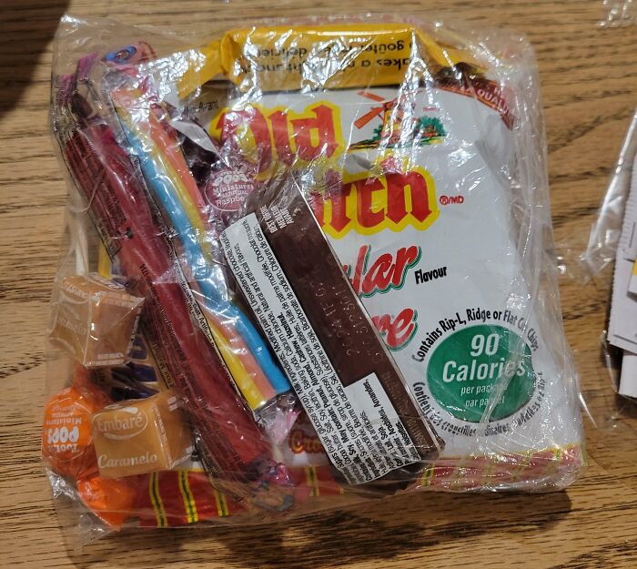 Bag of snacks and candies as company gifts bonuses on a wooden table.