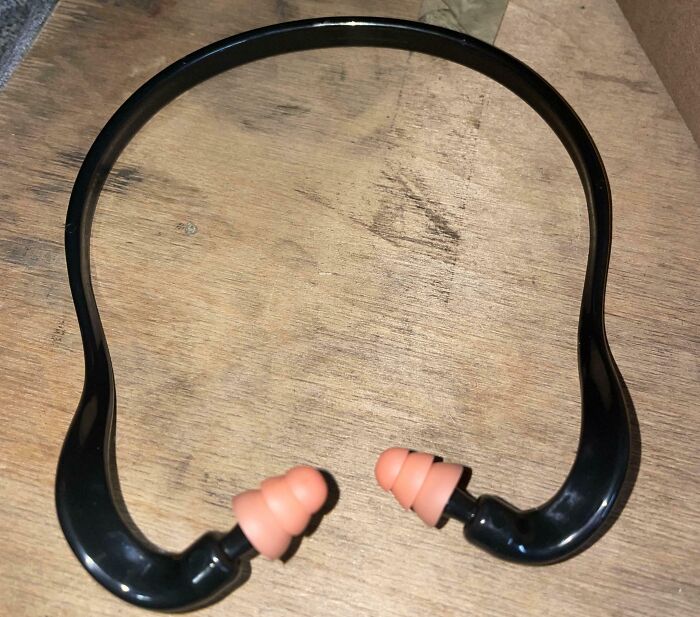Black neckband earplugs on a wooden surface, infuriating company gifts bonuses.