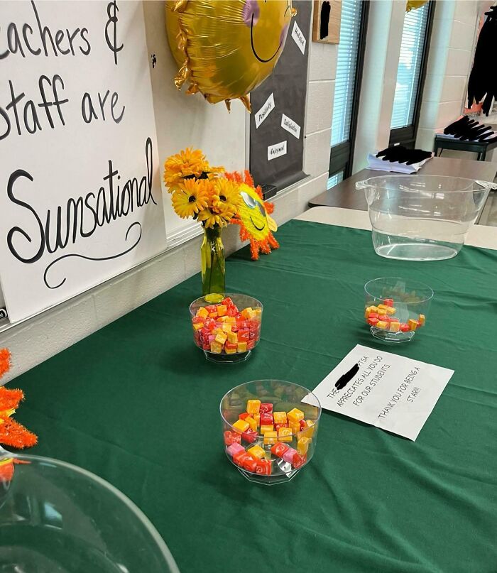 Bowls of candy on a table with a sign and flowers, symbolizing infuriating company gifts bonuses.