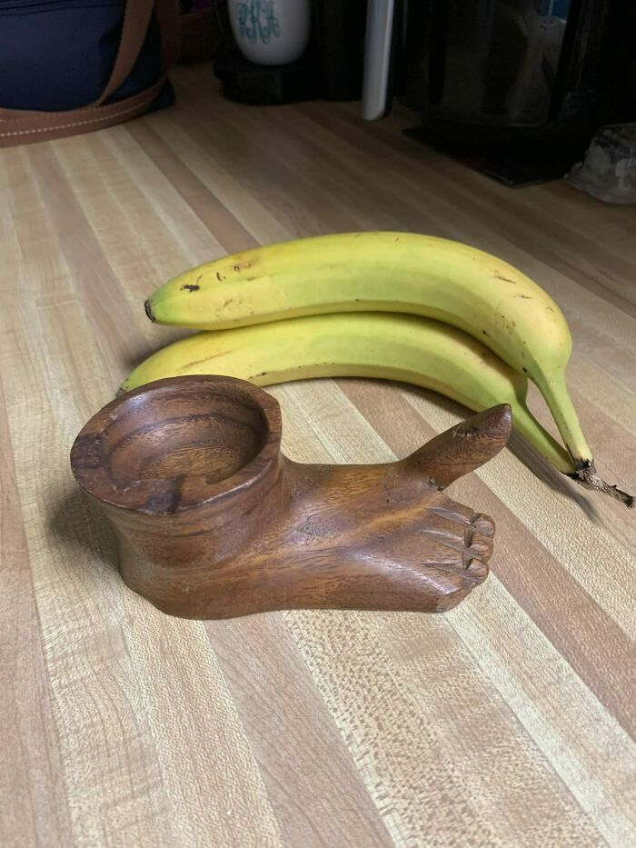 Wooden foot-shaped ashtray on a counter beside two bananas, a secondhand find.