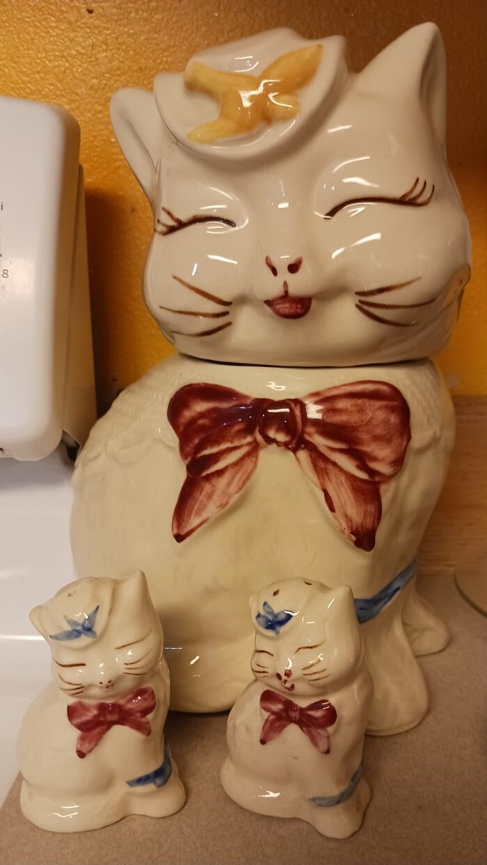 Ceramic cat cookie jar with kittens, a weird and wonderful secondhand find with colorful bows, on a kitchen counter.
