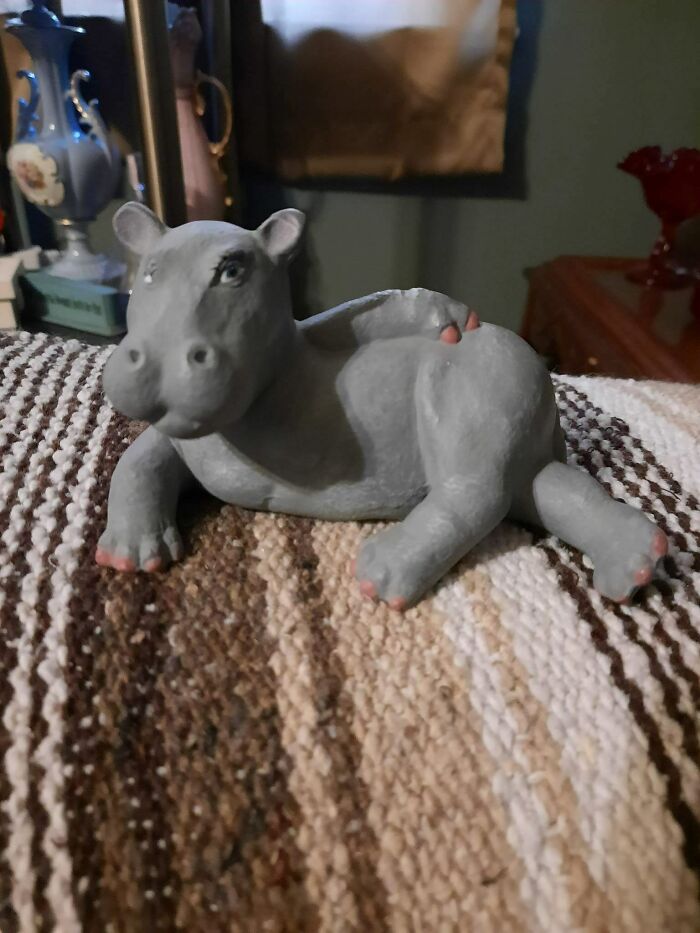 Gray hippo sculpture, found secondhand, placed on a textured surface with decorative items in the background.