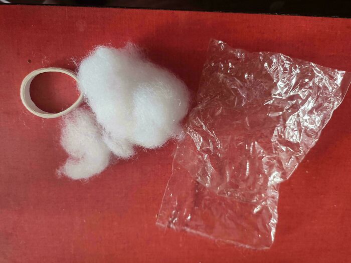 Clear plastic sheet, cotton fluff, and a tape loop on a red surface.