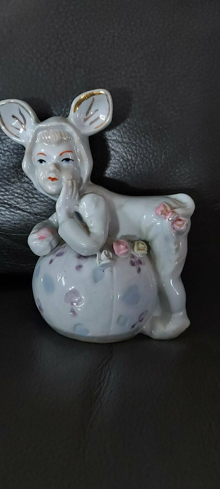 Quirky ceramic figurine with a child-faced deer, resting on a decorative ball, showcasing a weird secondhand find.