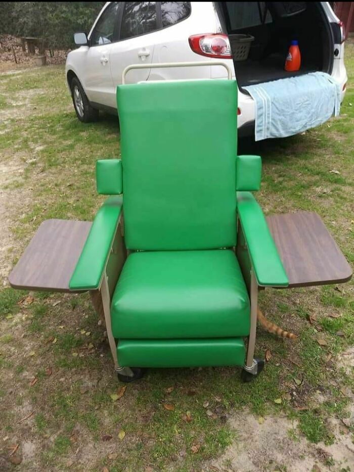 Green retro chair with wooden fold-out trays beside an open SUV, found secondhand.