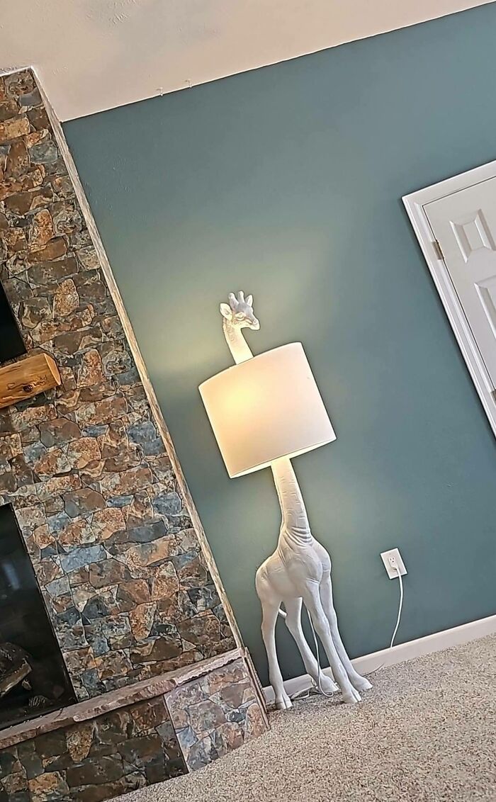 Giraffe-shaped lamp as a weird secondhand find beside a stone fireplace and teal wall.