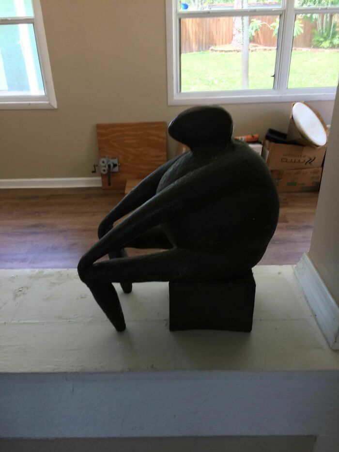 Weird secondhand find: abstract black sculpture of a figure sitting with arms wrapped around knees.