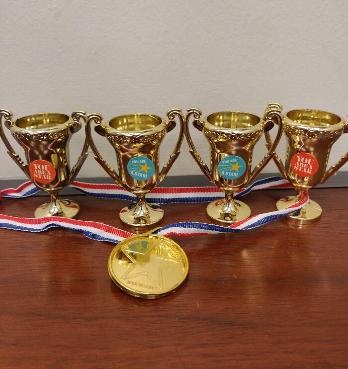 Four small gold trophies and a medal labeled "You Are A Star," representing infuriating company gifts bonuses.