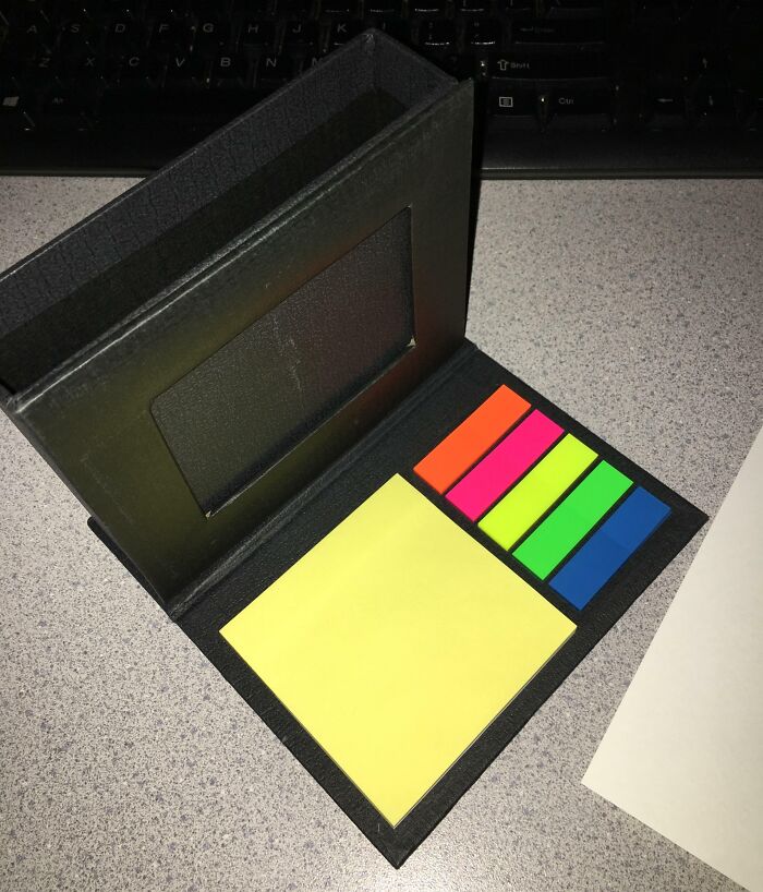 Gifts of multicolored sticky notes in a black holder on a desk.