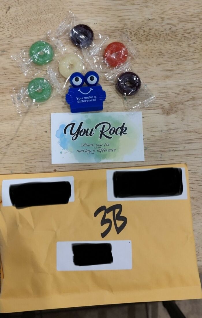 Small company gift with candies and a "You Rock" card on a wooden table, representing infuriating gifts.