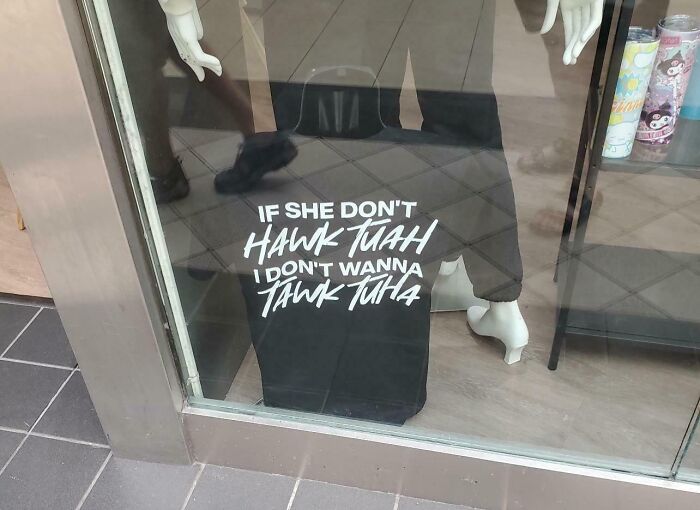 Shirt in store window with text suggesting being a jerk, as it reads "If she don't hawk juhah I don't wanna tawk tuhah."