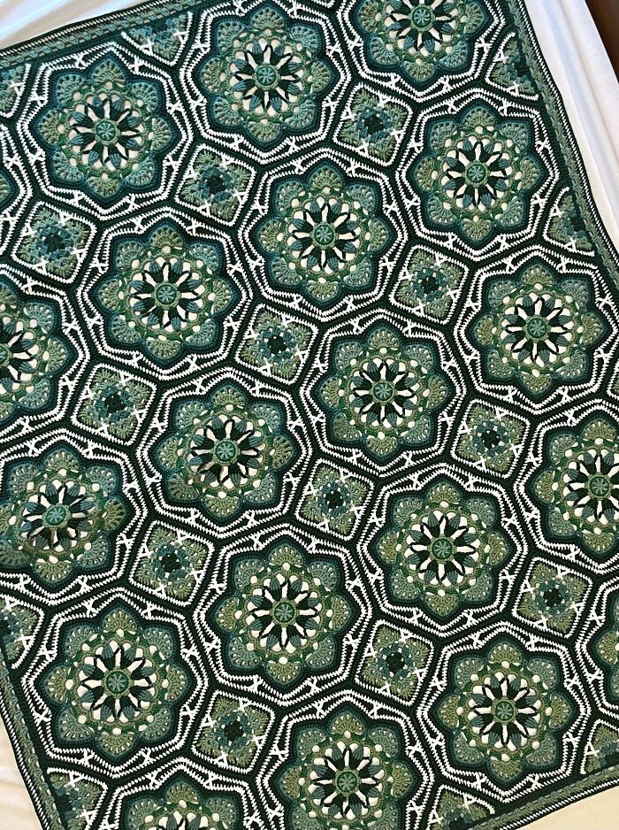 Intricate green and white crochet blanket with floral motifs showcasing detailed crochet masterpiece patterns.