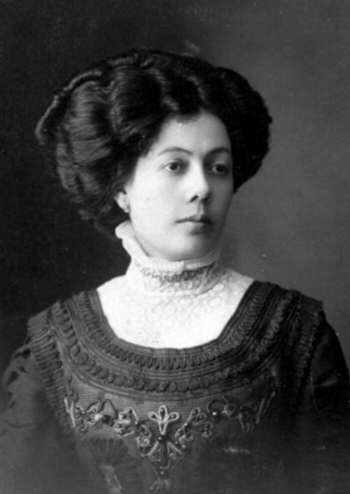 Historical portrait of a woman in an ornate dress, showcasing fashion from the early 20th century.