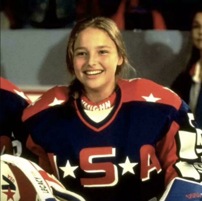 Young athlete in a '90s USA hockey jersey smiling during a game.