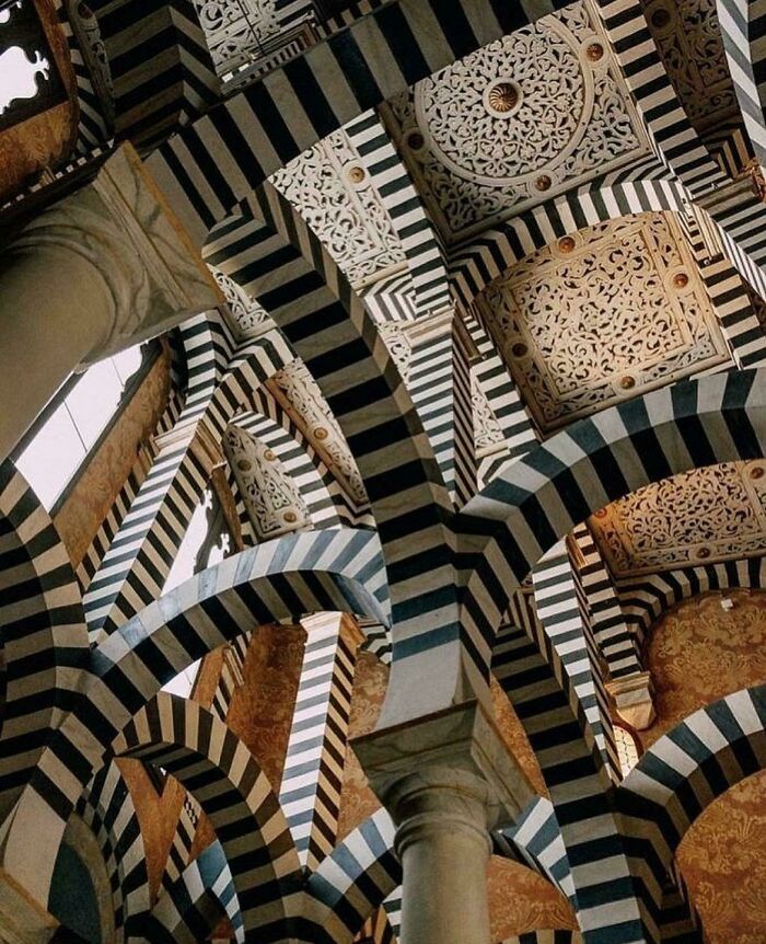 Intricate striped arches and detailed carvings showcasing impressive architectural feats in a historic building interior.