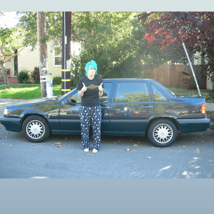 Person with blue hair standing barefoot in pajama pants next to an old car, part of people's regrettable past pics collection.