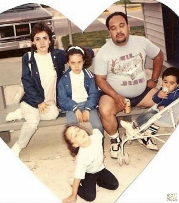 Awkward family photo of parents and children sitting and posing outside, capturing a sweet and candid moment.