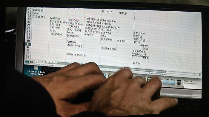 Close-up of hands typing errors on a cluttered spreadsheet, showcasing questionable movie details mocked by cinephiles online.