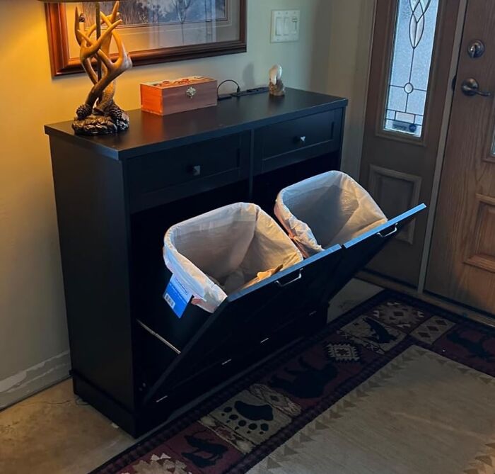 Hidden trash bins in a black cabinet by the entryway door, a neat solution to banish eyesores from your home.