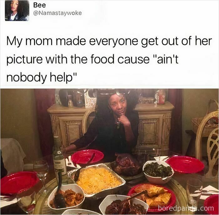 Woman posing proudly at a dining table filled with homemade dishes, embodying "moms behaving badly" humor.