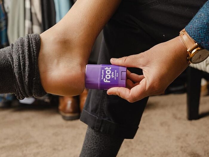 Applying affordable foot balm to heel, highlighting a 5-star rated item under $20.