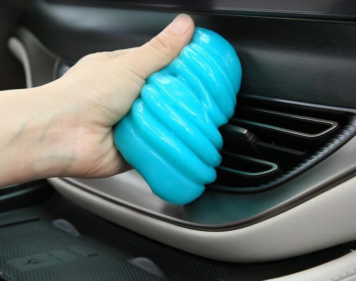 Hand using blue cleaning gel on car air vent, showcasing affordable 5-star items.