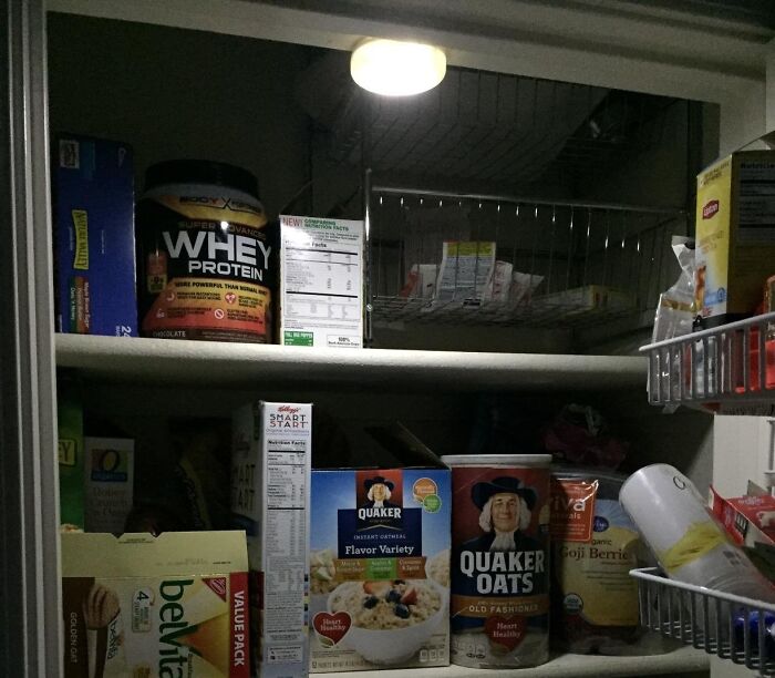 Pantry shelves stocked with affordable 5-star items, including oatmeal and whey protein, illuminated under a small light.