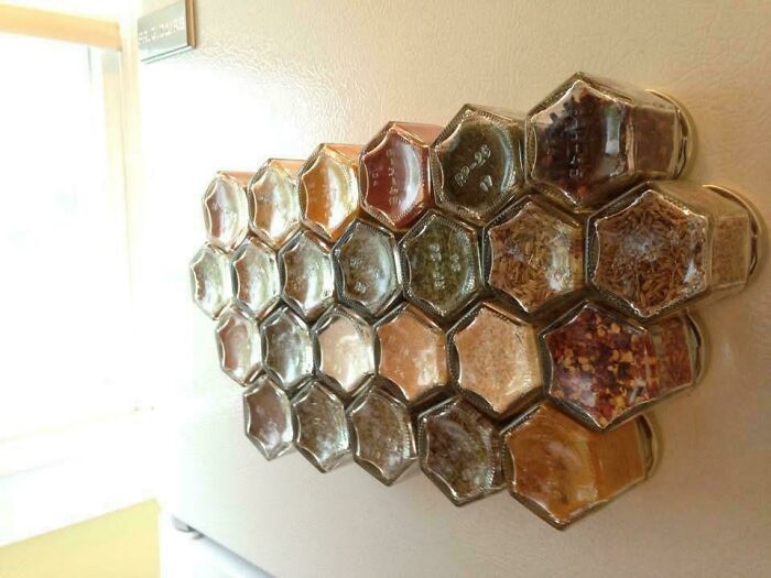 Hexagonal spice jars neatly organized on a kitchen wall, showcasing next-level organization in a visually satisfying pattern.