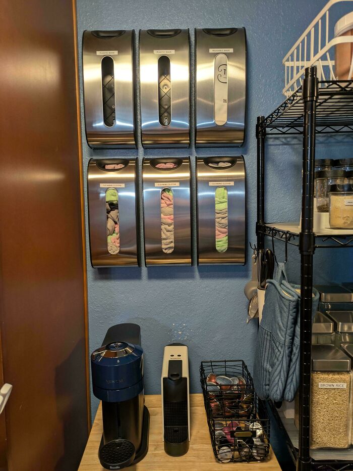 Next-level organization: neatly arranged wall dispensers, coffee machine, and shelf with jars in a tidy kitchen corner.