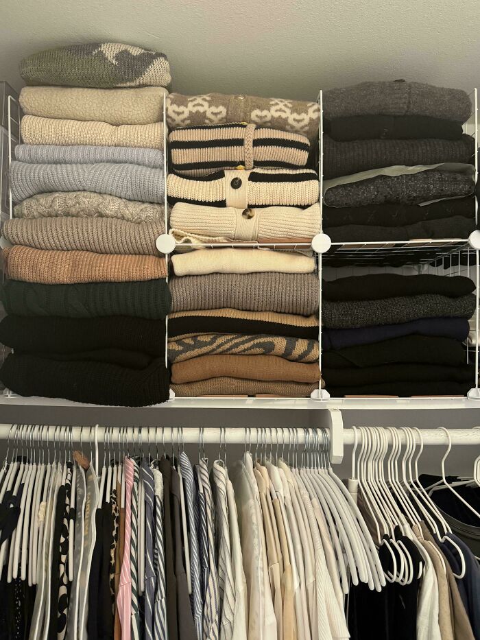 Neat organization of sweaters and shirts in a closet, showcasing next-level tidiness and satisfying results.
