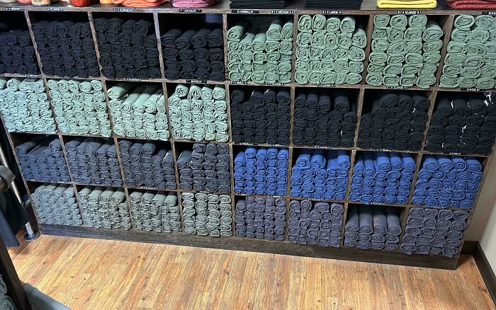 Neat rows of colorfully organized towels on shelves showcasing next-level organization.