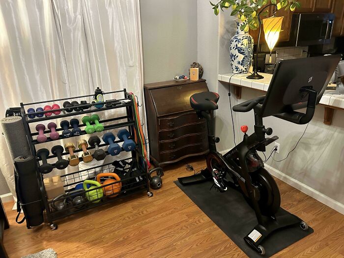 Neatly organized home gym with weights rack and exercise bike in a tidy setup.