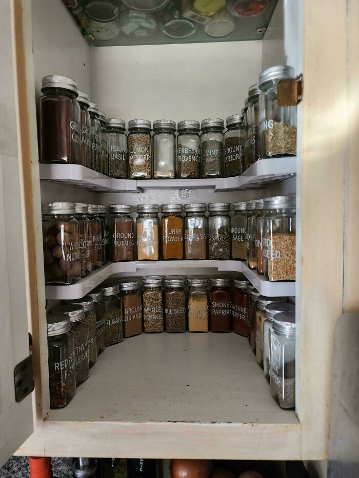 Neat organization of spice jars labeled and arranged in a kitchen cabinet.