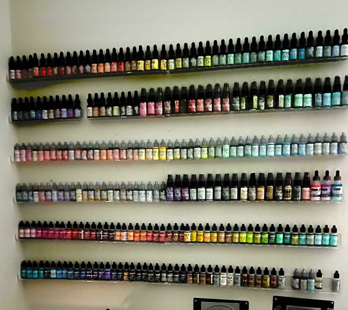 Neat results of next-level organization: rows of colorful bottles neatly arranged on shelves against a light-colored wall.