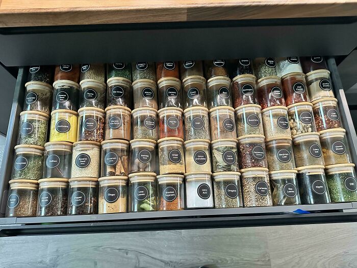 Neat organization of spices in labeled jars inside a kitchen drawer.