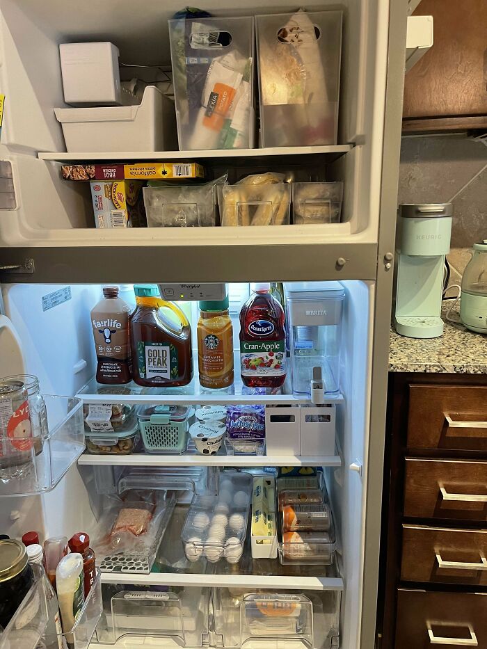 Highly organized refrigerator interior showcasing neat arrangement of beverages, eggs, and containers.