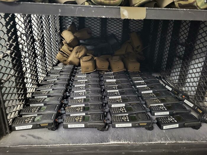 Neat organization of radios and pouches in a metal cabinet.