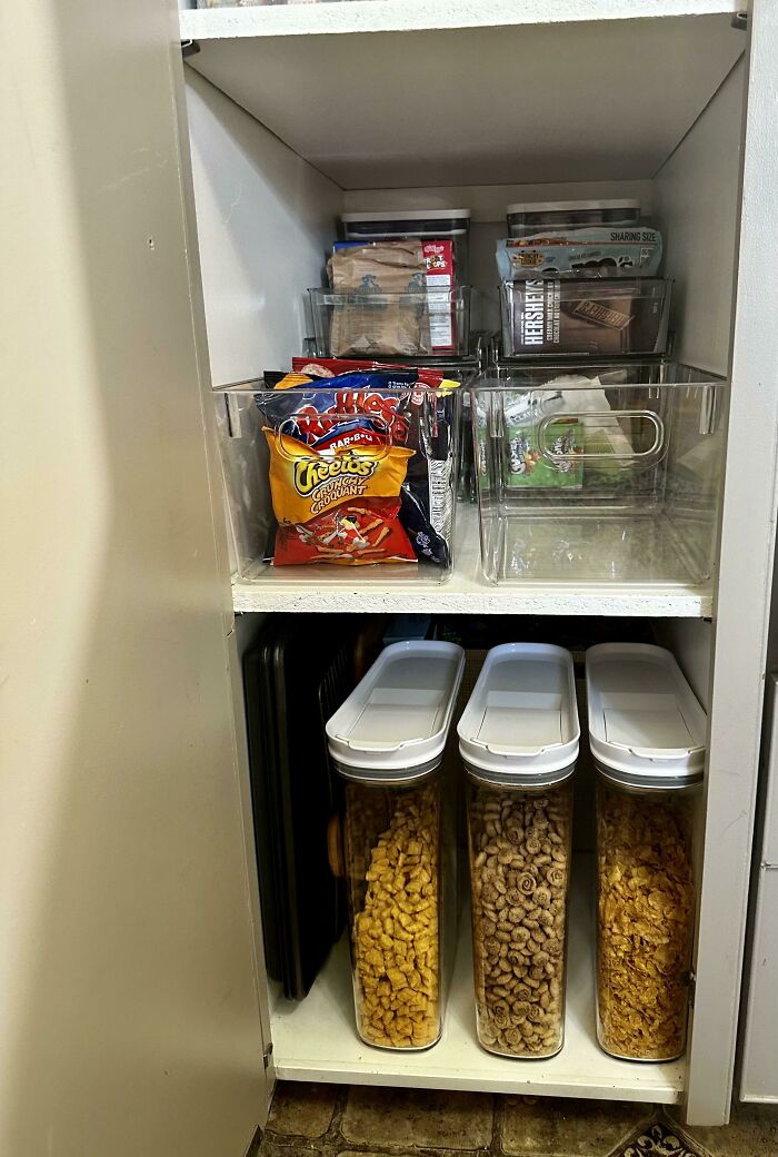Organized pantry with neatly arranged snacks and cereals in clear containers.
