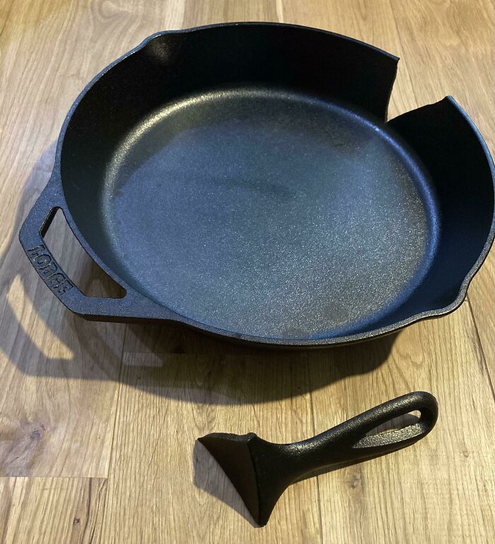 Low-quality item with a broken cast iron skillet handle on a wooden floor.