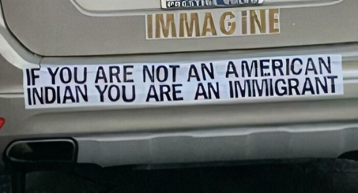 Bumper sticker with humorous message on a car, discussing immigration.