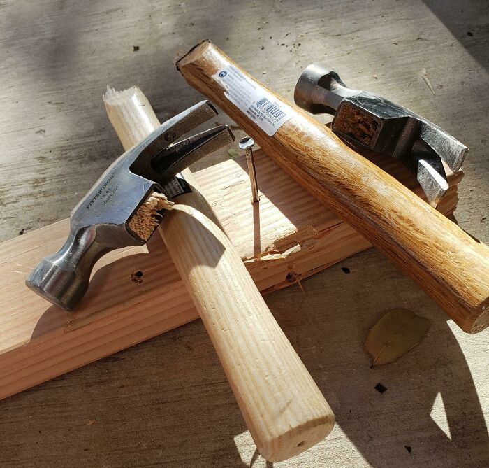 Low-quality items: two broken hammers on a wooden plank, showcasing ineffective tools purchased for work.
