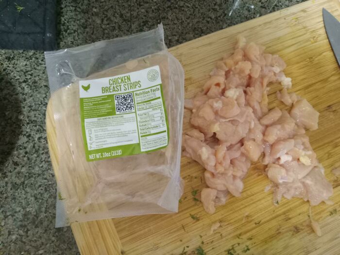 Low-quality chicken breast strips on a wooden cutting board.