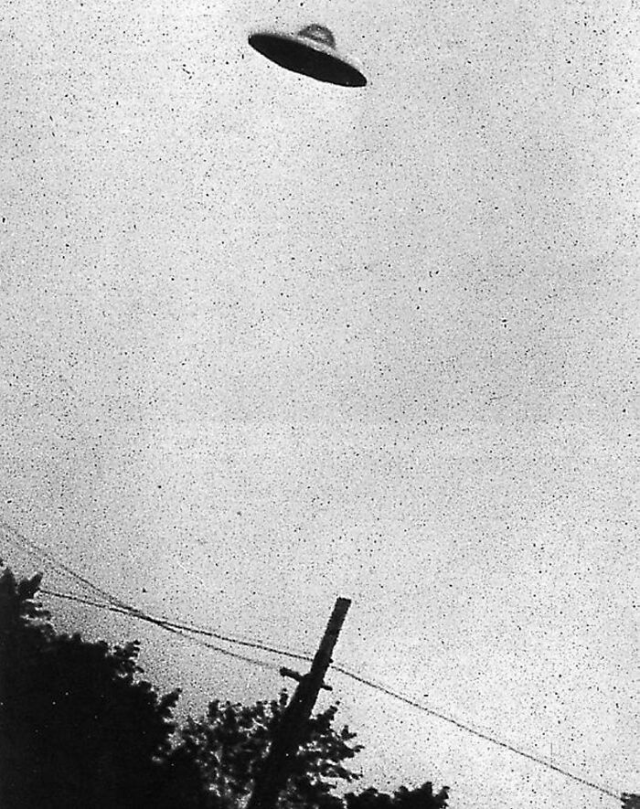 "Classic UFO disc-shaped object in the sky, representing weird unresolved mysteries."