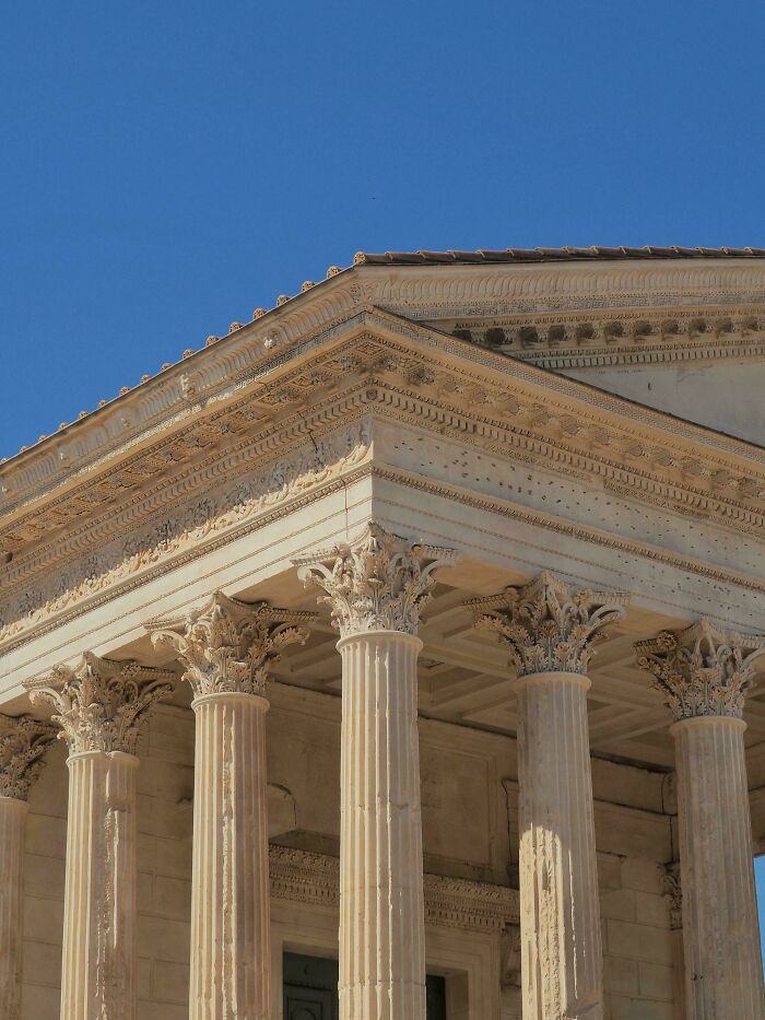 Classical architectural feat featuring ornate Corinthian columns and detailed entablature under a clear blue sky.
