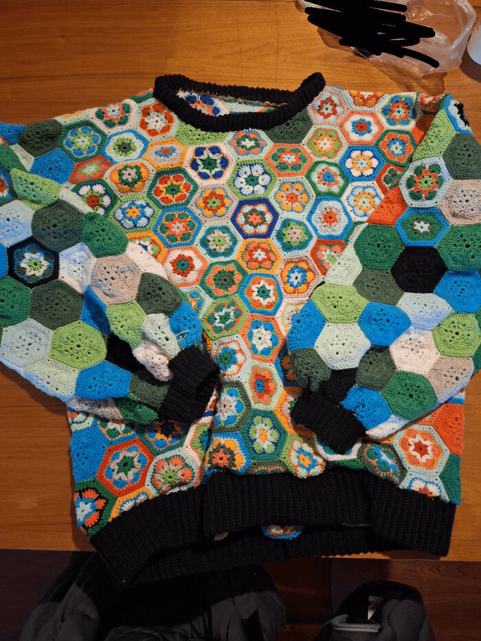 Colorful crochet sweater made of hexagonal motifs in various colors, showcasing intricate crochet craftsmanship and design.