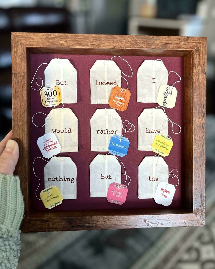 Embroidery art embroidered on tea bags displaying a quote about tea, showcasing beautiful embroidery skills in a wooden frame.