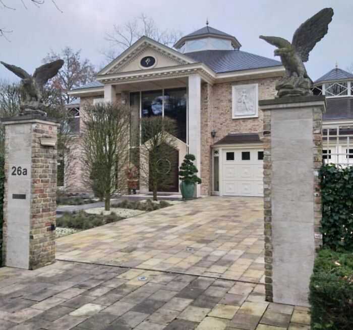 Elaborate house facade with eagle statues at the gate, showcasing unique architectural design.