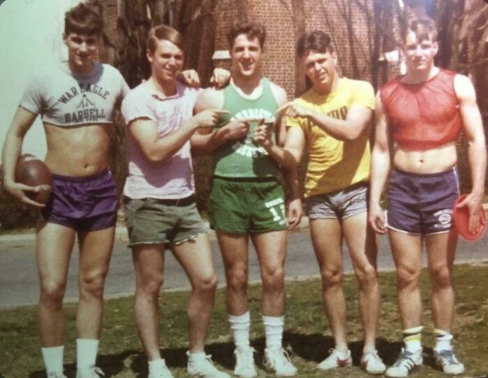 Group of young men sporting 80s fashion trends, wearing shorts and colorful tops, posing outdoors with a football.