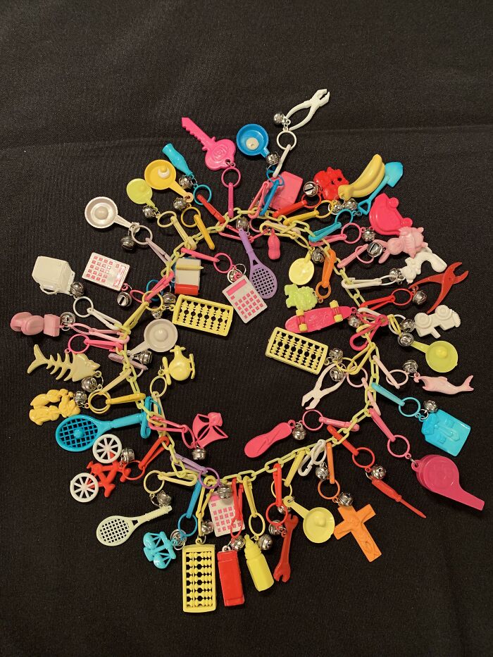 Colorful 80s fashion trend keychains with various charms and trinkets arranged in a circle on a dark background.